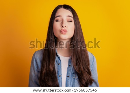Portrait of a lovely pretty woman sending air kiss close eyes on yellow background