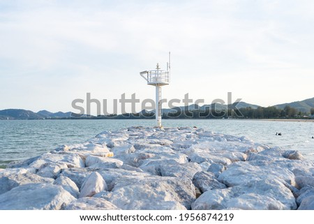 The​ view​s​ beautiful​ white​ light​house​ on pile of rocks to block the waves of the sea.