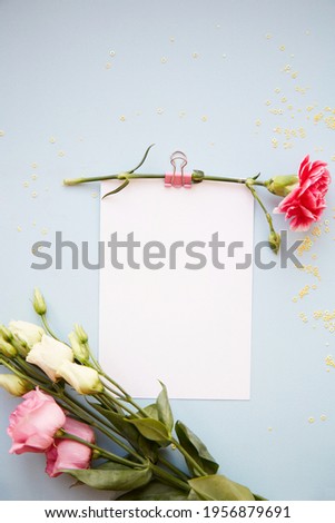 Festive still life. White card mockup on blue background with eustoma flowers and decorative astra. Summer fashion background