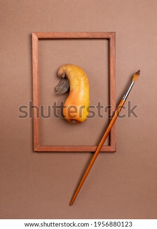 Wooden frame with ugly ripe pear inside it and brush on brown background.