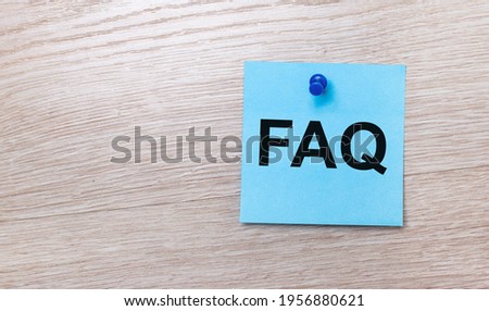 On a light wooden background - a light blue square sticker with the text FAQ