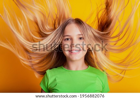 Portrait of little cheerful funny lady posing wind blow hair on yellow background