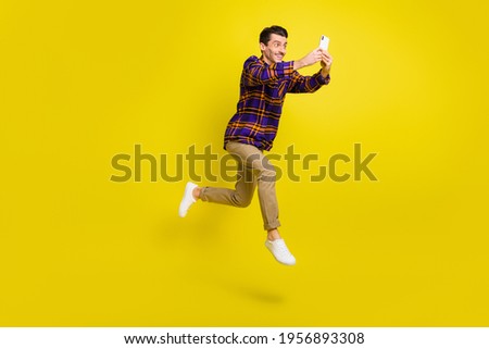 Full size profile side photo of young man happy smile jump go walk run chat type cellphone isolated over yellow color background