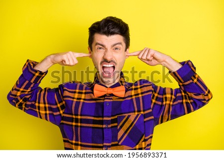 Photo of young man unhappy irritated annoyed close ears fingers loud noise isolated over yellow color background