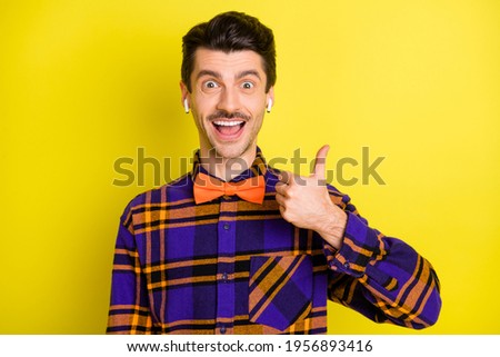 Photo of young excited man happy positive smile show thumb-up advice like earphones isolated over yellow color background