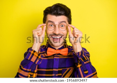 Photo of young handsome man happy positive smile hands touch eyeglasses isolated over yellow color background