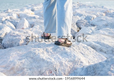 Legs of a young woman on pile of rocks to block the waves of the sea.