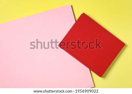 Book with red cover on color background, top view. Space for text