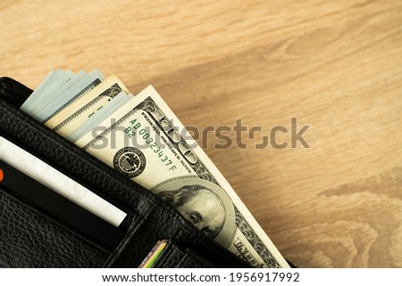 Laptop and wallet with credit card and cash money on a wooden desktop, online payment systems and banking concept.