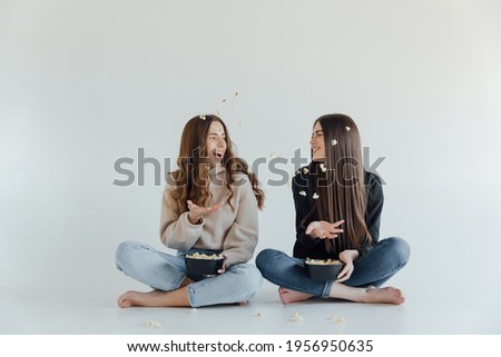 Smiling young women relaxing and watching TV at home, female friends having rest after hard week, copy space