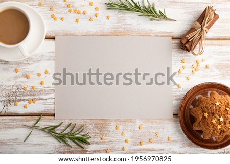 Gray paper sheet mockup with cup of coffee and cake on white wooden background. Blank, top view, flat lay, still life.