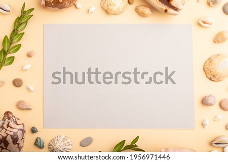 Composition with gray paper sheet, seashells, pebbles, green boxwood. mockup on orange background. Blank, top view, still life, flat lay, copy space. travel concept.