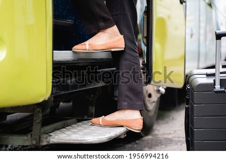close up of the feet of a woman in shoes stepping up the bus door steps before leaving by bus Royalty-Free Stock Photo #1956994216