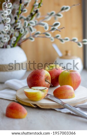 Still life. There are apples on the table. There are willow branches in a ceramic vase. Spring. Warmth and comfort emanate from photography. Apple sliced into wedges