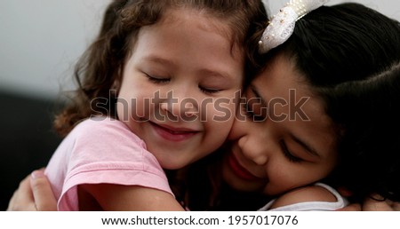 Little girl kissing and hugging sibling sister, family love affection