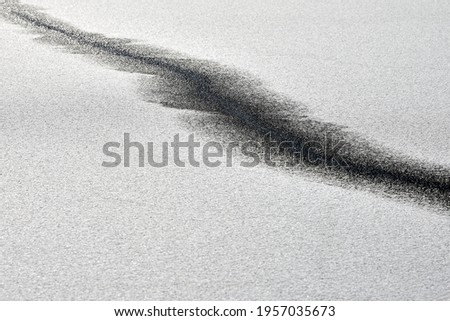 Abstract black line on snow-white background. Black and white minimalist art, contrast achromatic. Melting ice covered with snow. Landscape for postcard, poster, banner.