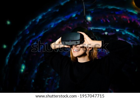 A girl using glasses for virtual reality smiles and plays a video game. VR games.