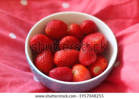 Bowl of strawberries and open book on a bed. Selective focus.