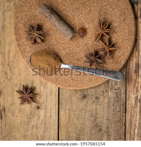 Spices on a wooden table . Spices for cooking with a copy space.  Indian spices on a tea spoons .   Cinnamon powder and anis stars on a wooden table with a copy space. 
