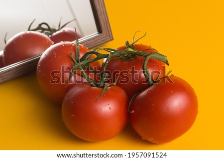Red ripe tomatoes on the yellow table next to the mirror. Laying out food and vegetables in the kitchen.