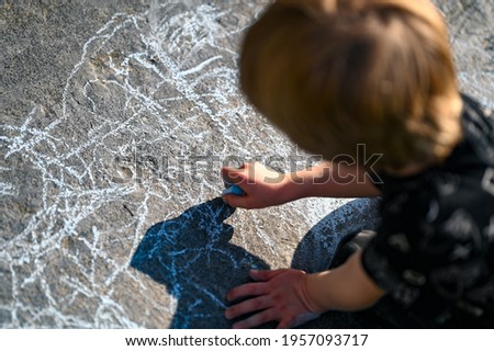 Boy Drawing Chalk Hand Painting in the Sun