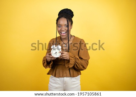 African american woman wearing casual clothes screaming and scared, pointing the clock