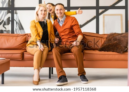 Happy young family with small kid sit relax cuddle on couch together watch movie on laptop, smiling parents rest on sofa enjoy spending weekend with preschooler daughter see cartoon on computer.