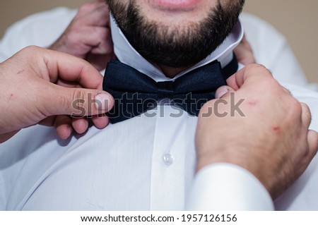 Blue bow tie in the hands of the groom. Bow tie in the hands of a man