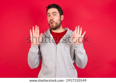 Young caucasian man wearing tracksuit over red background Moving away hands palms showing refusal and denial with afraid and disgusting expression. Stop and forbidden.