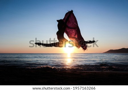 girl dancing on the sand while the sun is setting behind her 
