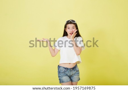 Young elegant beautiful Asian woman smiling and pointing to empty copy space isolated yellow bright color background