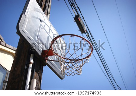 Urban basketball hoop on telephone pole in alley with power lines
