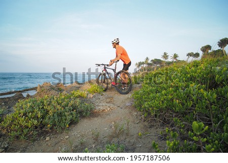 Man with mountain bike enjoying ocean view. Wide angle.
