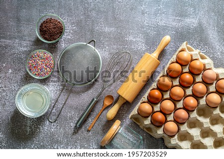 Eggs and bread making equipment,Pictures of ingredients for making cakes bakery around, such as eggs, flour, sugar, butter, recipe book and equipment for making on a wooden floor, with copy space.