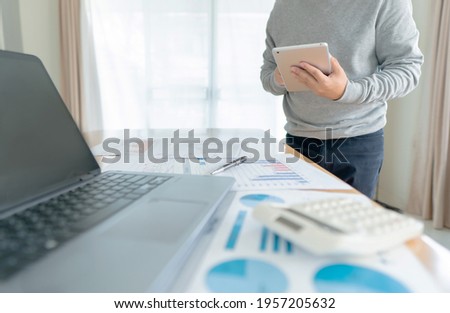 Businessman in casual wear stands beside desk to work at home with tablet. work from home concept.