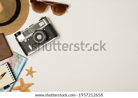 Top view photo of headwear sunglasses camera map passport cover starfishes pen and notebook on isolated wooden white background with copyspace on the right
