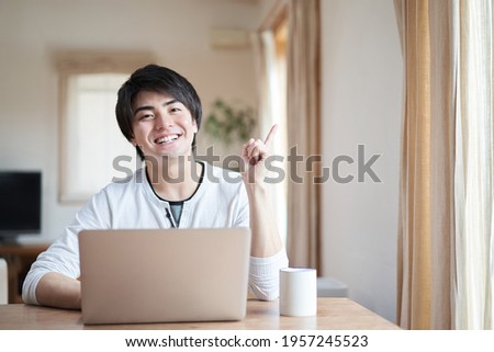 Asian man pointing while operating a computer Royalty-Free Stock Photo #1957245523