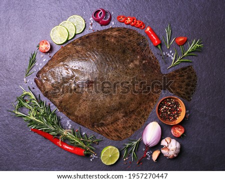 Flounder fish on black background with spices and vegetables