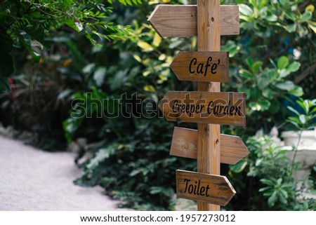 Wooden signs indicating the entrance to the cafe, garden and restroom.