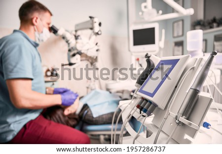 Close up of modern dental apparatus for endodontic obturation of root canal with stomatologist and patient on blurred background. Dentist checking woman teeth. Concept of dentistry, dental equipment. Royalty-Free Stock Photo #1957286737
