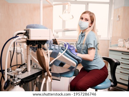 Young female dentist holding dental instruments, sitting beside patient with inhalation sedation at dental office. Concept of sedation dentistry and dental care. Royalty-Free Stock Photo #1957286746
