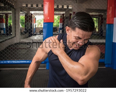 A fit man experiences rotator cuff tear, sprain or injury during a workout session at the gym. Royalty-Free Stock Photo #1957293022