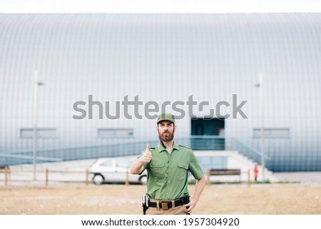 security guard in uniform and armed working on the safety of buildings on a sunny day