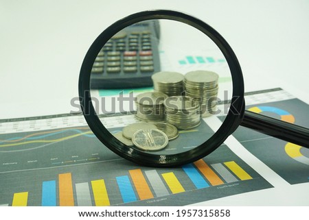magnifying glass, coin and calculator with charts on financial reports. Business and financial concepts
