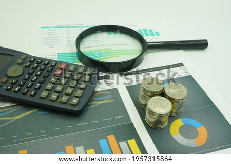 magnifying glass, coin and calculator with charts on financial reports. Business and financial concepts