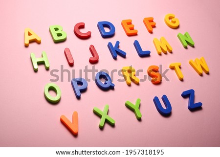 alphabet from multicolored plastic magnet letters on a pink background