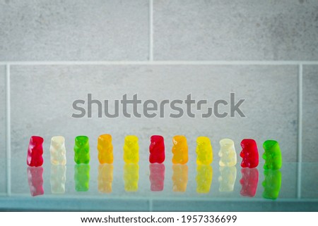 multicolored chewing gummy bears  in a row on gray background