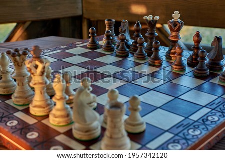 Chess wooden pieces close up on a game board on the background of the window and interior
before the battle