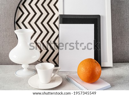 Composition with empty picture frame,notebook,vase,cup of coffee and snack. Elegant working place. Scandinavian interior design.Home office concept. 