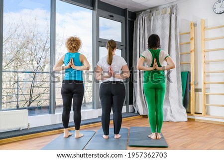 Three fit women stand with hands back